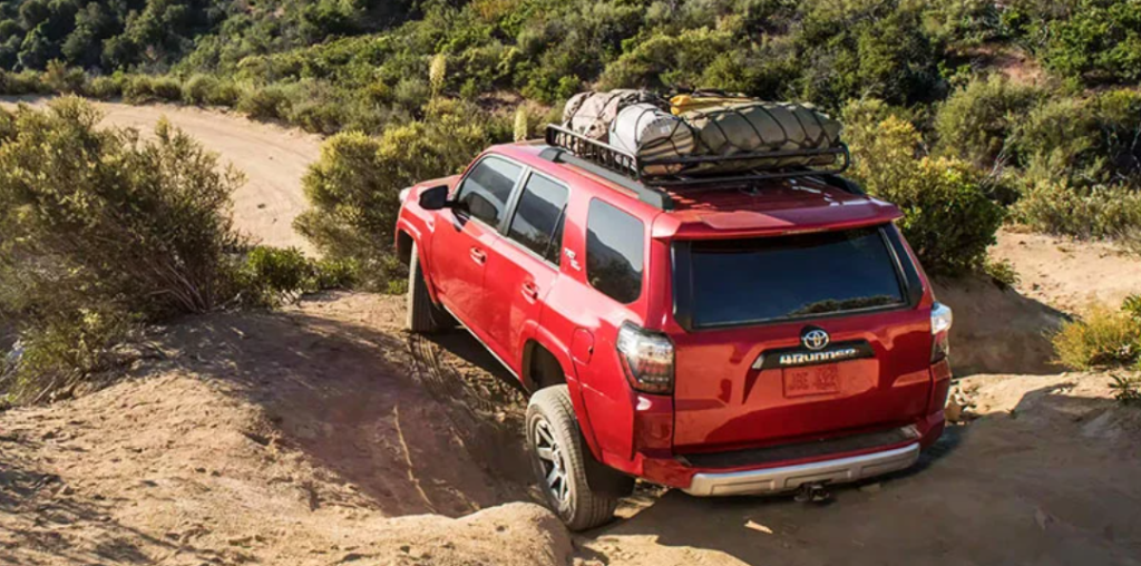 A red 2023 Toyota 4Runner with camping gear packed on top is parked over a mountain lookout.