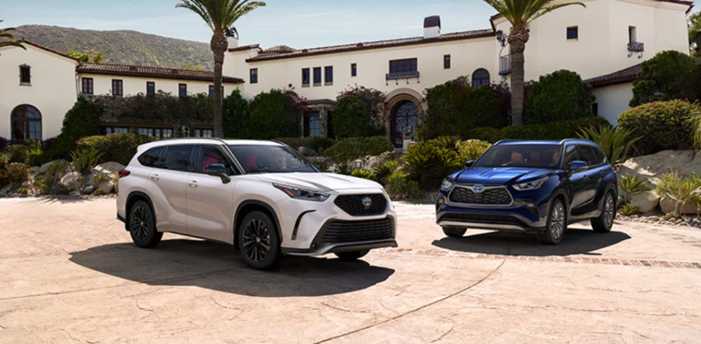 A white and a blue 2023 Toyota Highlander parked in front of a villa.