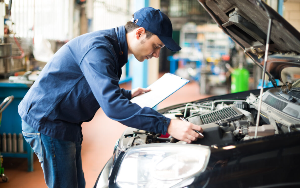An auto repair service technician inspecting a vehicle.