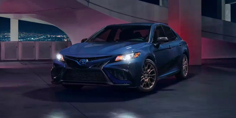 A 2024 Toyota Camry Hybrid with headlights on in the dark.