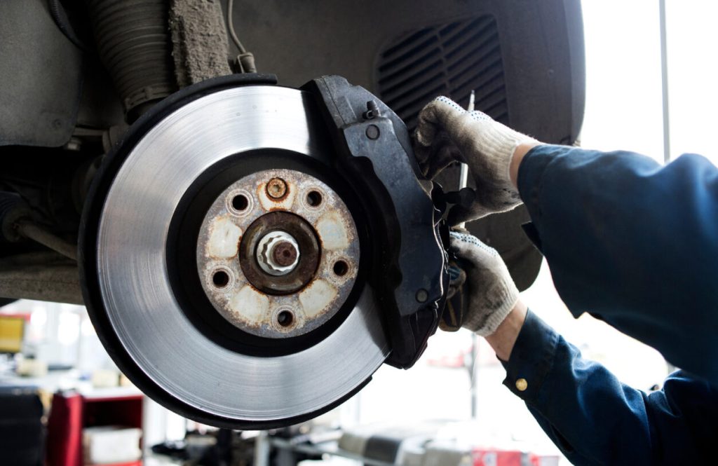 Exposed vehicle brakes and an auto repair technician is working on them.