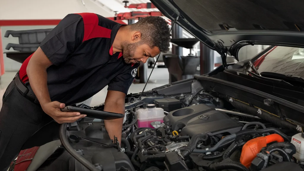 Technician inspecting a vehicle engine bay during routine maintenance.